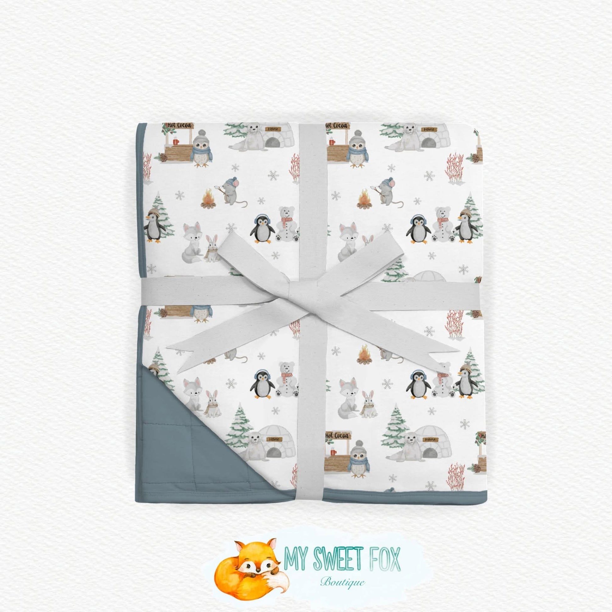 Arctic animal bamboo blanket wrapped in a light gray ribbon and tied with a bow, displayed on a textured white background. The bottom corner of the blanket is turned over to show a solid gray backing.