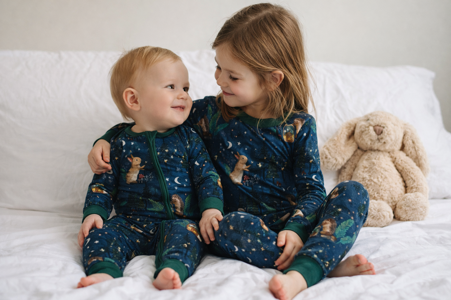 Baby and older sister sitting togher in their woodland bamboo jammies and enjoying the soft bamboo jammies. 