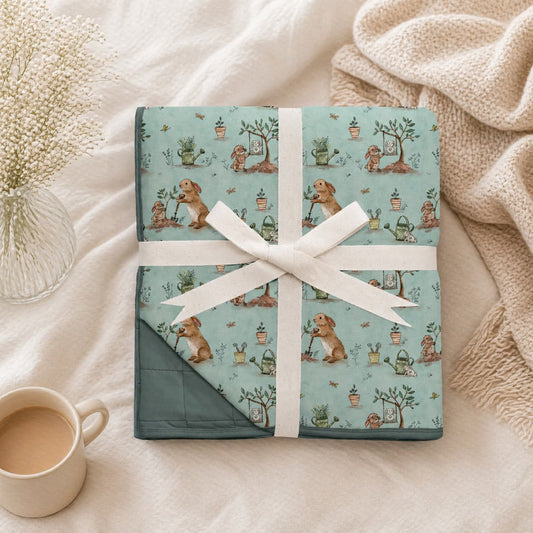 Blue bamboo blanket with bunnies and garden print wrapped in a white ribbon on a soft surface with a cup of coffee.