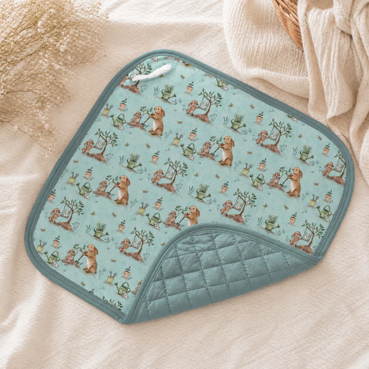 Quilted bamboo lovey washcloth with bunny and garden pattern on a beige surface