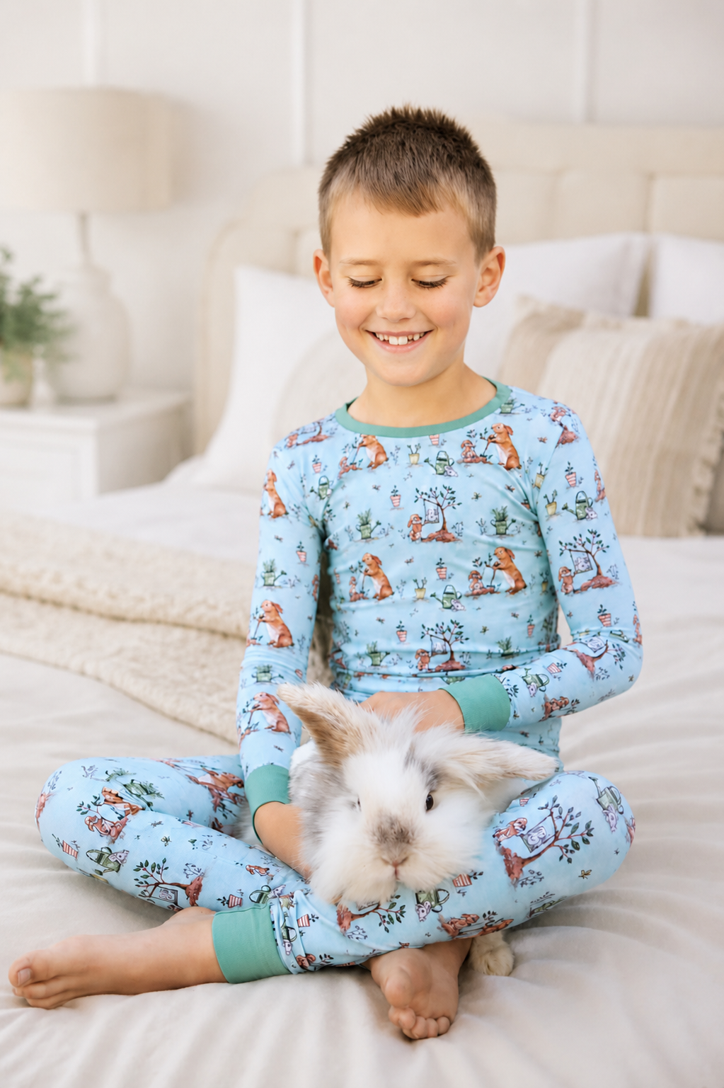 Child wearing bamboo pajamas with bunny pattern sitting on a bed with a rabbit.