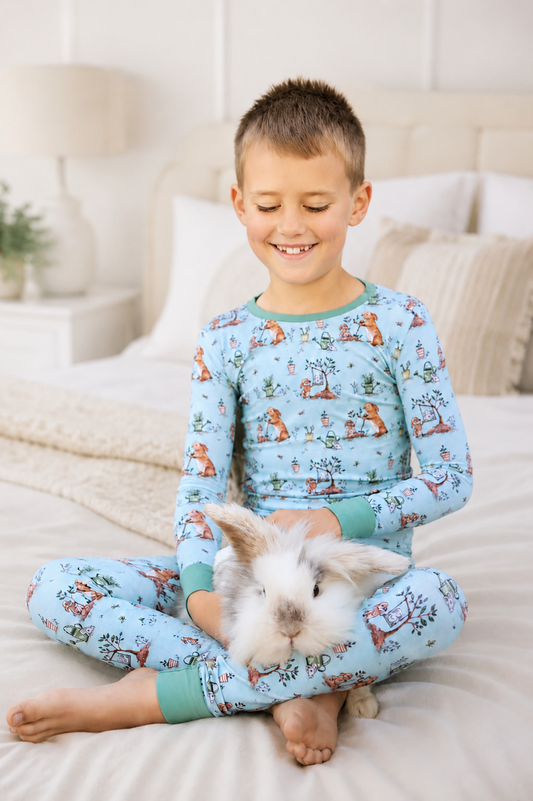 Child wearing bamboo pajamas with bunny pattern sitting on a bed with a rabbit.