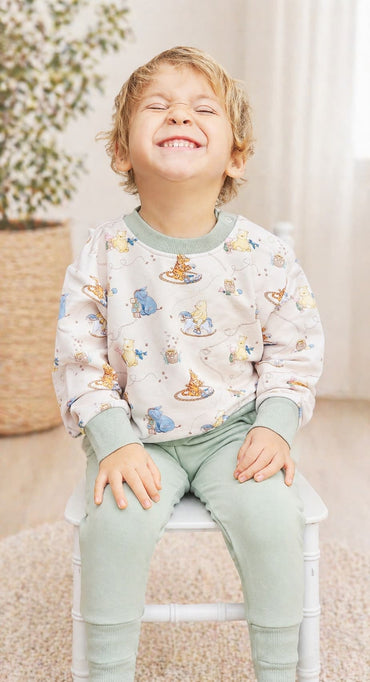 Child wearing a Classic Pooh bamboo french terry set sitting on a chair.