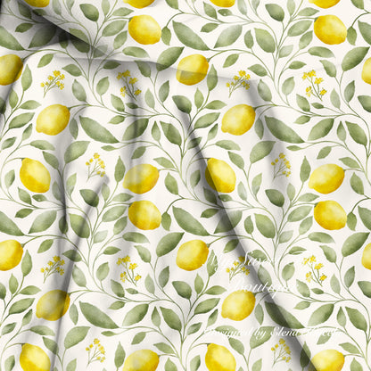 Watercolor lemon and leaf patterned bamboo viscose fabric with yellow lemons, green leaves, and small yellow flowers on a white background, shown with soft folds.