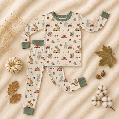 Children's bamboo pajama set with woodland, apples, and orchard print. Bamboo pajamas is on a beige fabric background with autumn elements.
