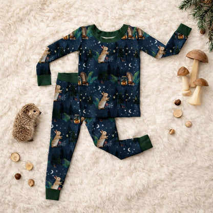 Children's bamboo pajama set with woodland forest animal print on a textured surface with woodland and mushroom decors.