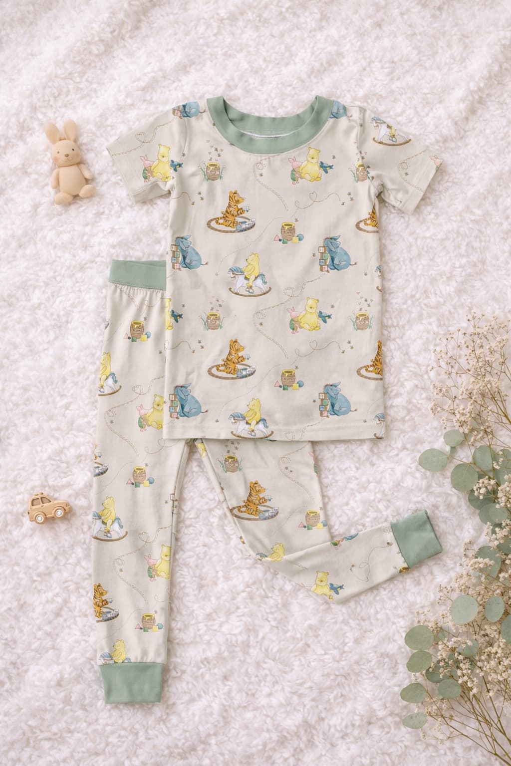 Bamboo pajamas set with classic Pooh, tigger, eeyore, and piglet on a cream background with sage as the coordinating color. 