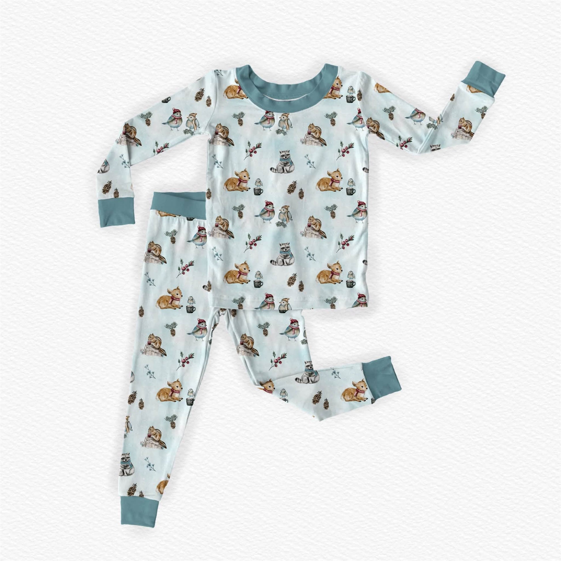 Children's woodland bamboo pajama featuring a winter woodland theme. Hand drawn details of woodland animals like fawn, raccoon, chipmunks and songbirds dressed in scarf and beanies sharing hot cocoa. 