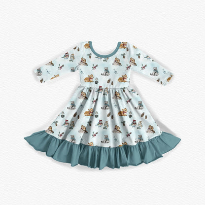 Long-sleeve bamboo dress with a winter woodland animal design. Featuring raccoons, fawns, chipmunks, and songbirds sharing hot cocoa on a snowy winter day. Teal neckline and ruffles for the bamboo twirl dress. 