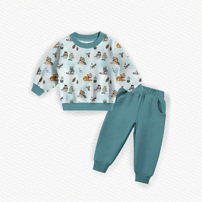 Children's French terry bamboo outfit set featuring a light blue long-sleeve sweatshirt with a colorful woodland animal print and solid teal trim, paired with matching teal sweatpants, laid flat on a white textured background.